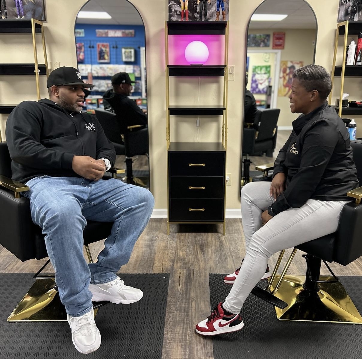 Sean and Ragan sitting in the barber chairs inside Cuts And Comics